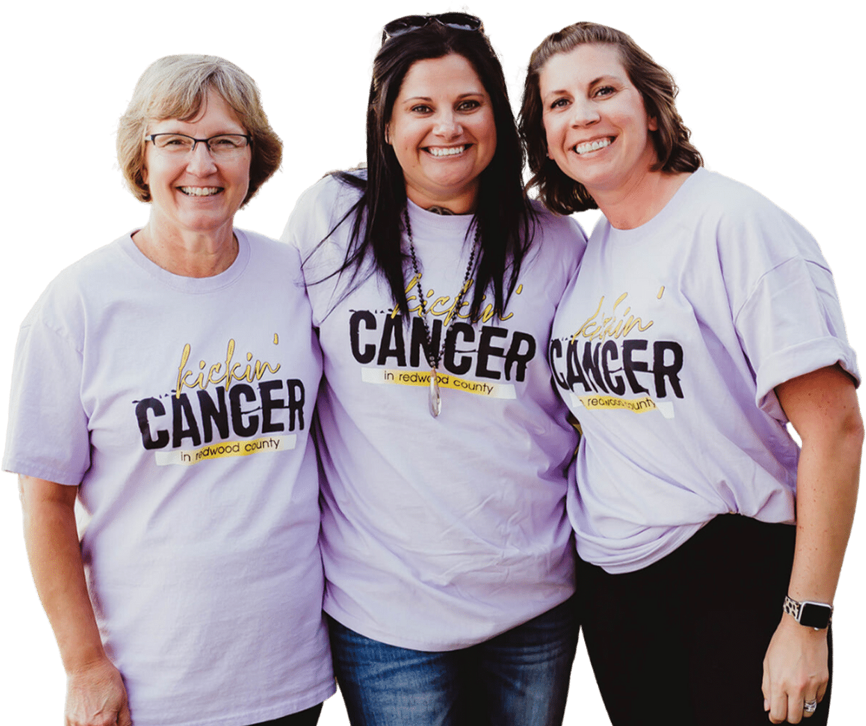 Three women proudly posing for a photo in Kickin' Cancer Redwood County t-shirts to raise awareness.