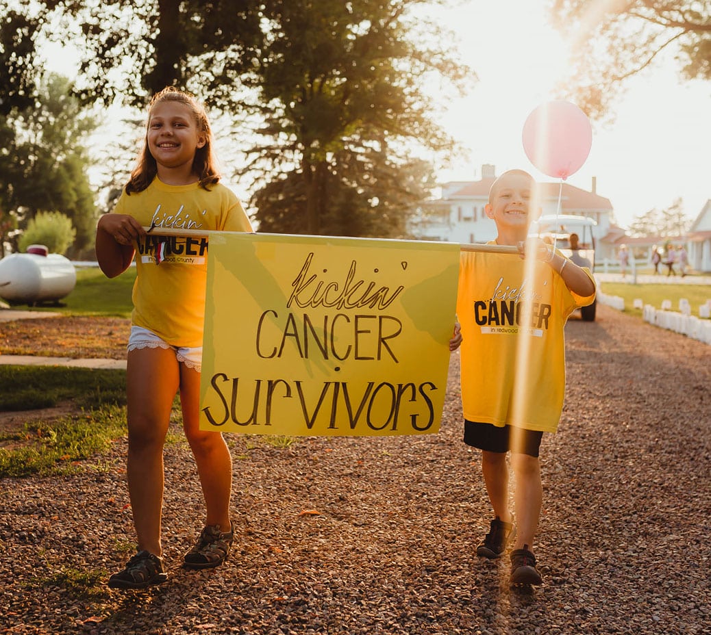 Two children holding a Kickin' Cancer sign.