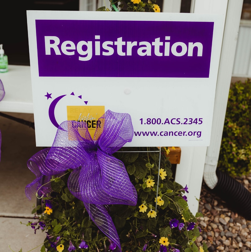 A purple sign with a purple ribbon on it displaying "Registration".