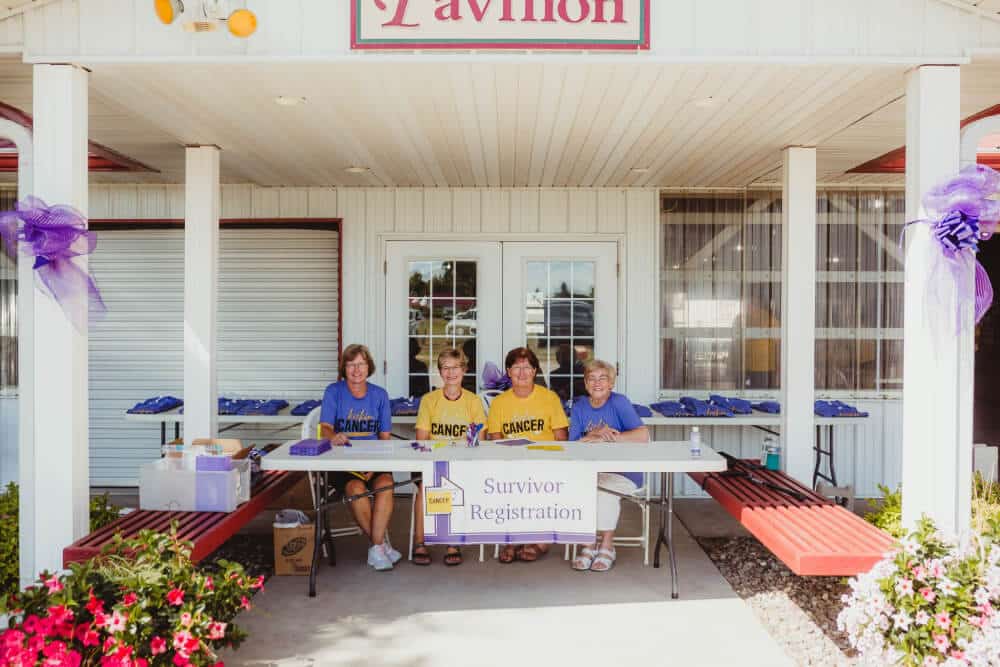 A group of cancer patients sitting at a table in front of a building for support.