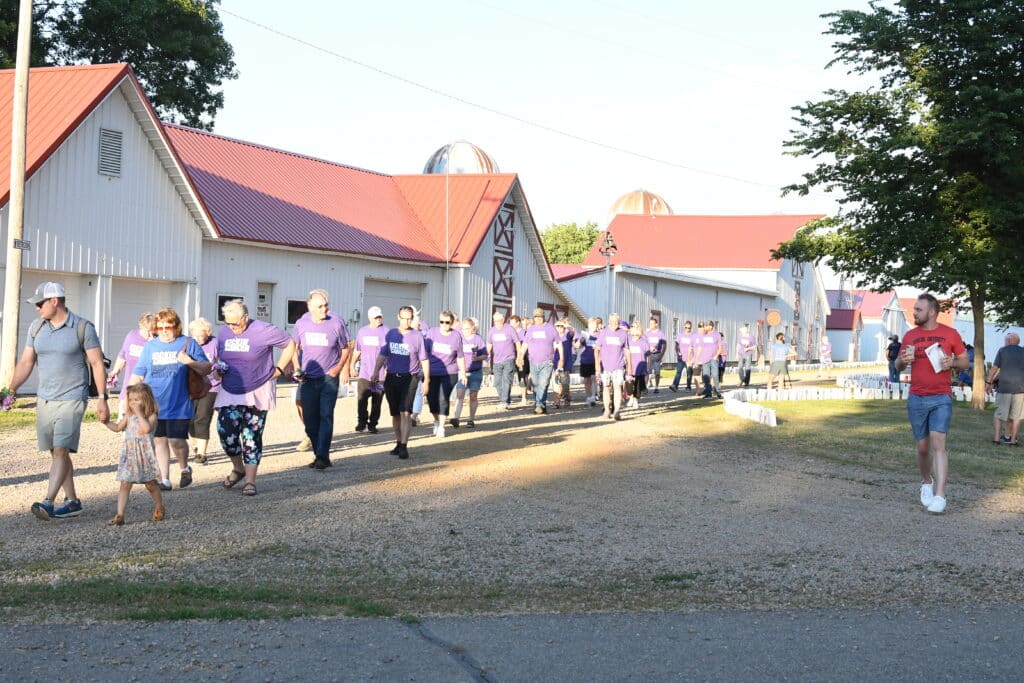 A group of people walking down a dirt road to celebrate the 3rd Annual Kickin' Cancer Event success.