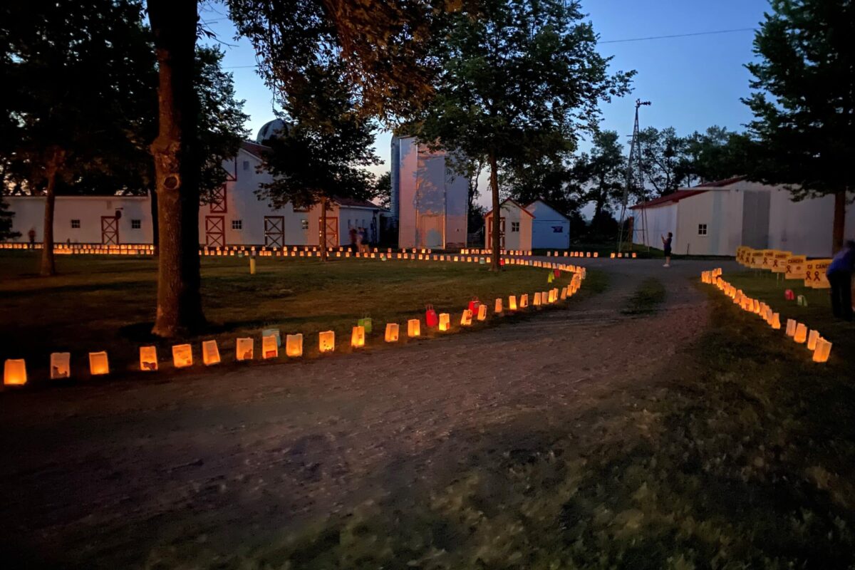 People walk down a path filled with luminaries