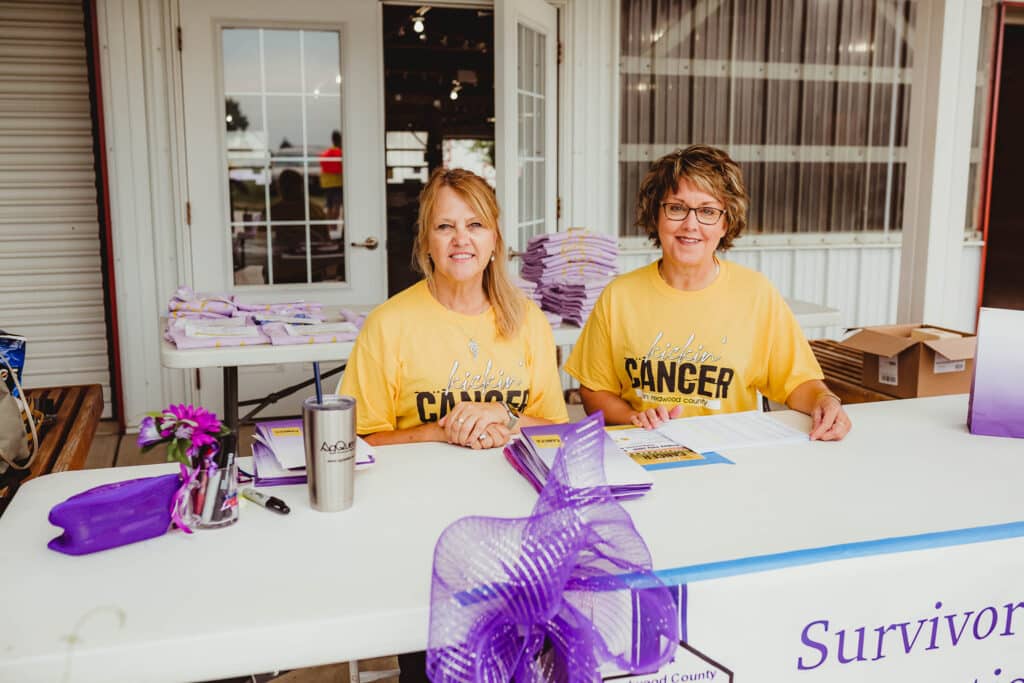 Two women in purple shirts at an annual kickin cancer event.