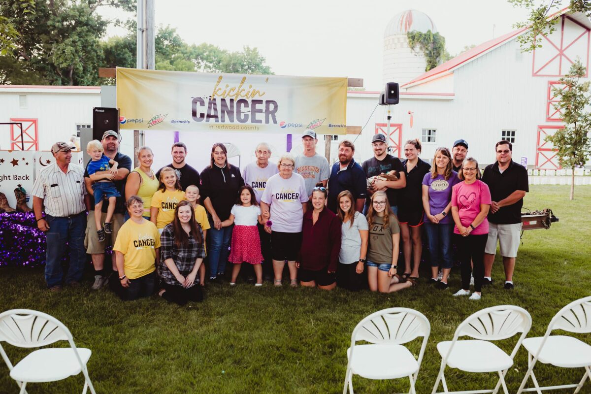 A group of people in front of a kickin' cancer event banner