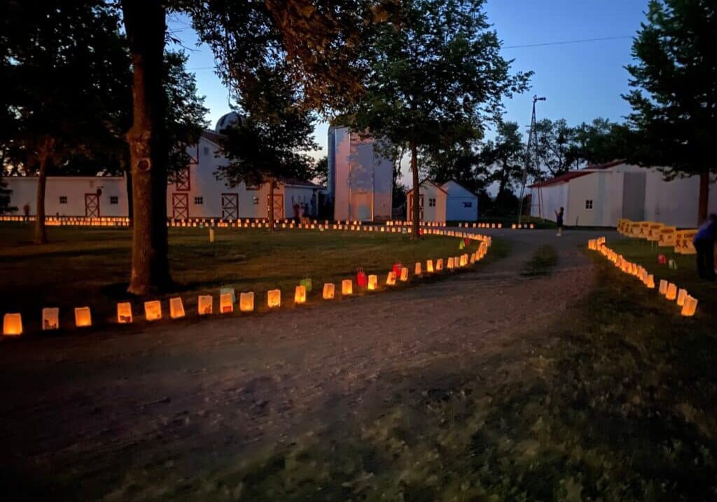 People walk down a path filled with luminaries