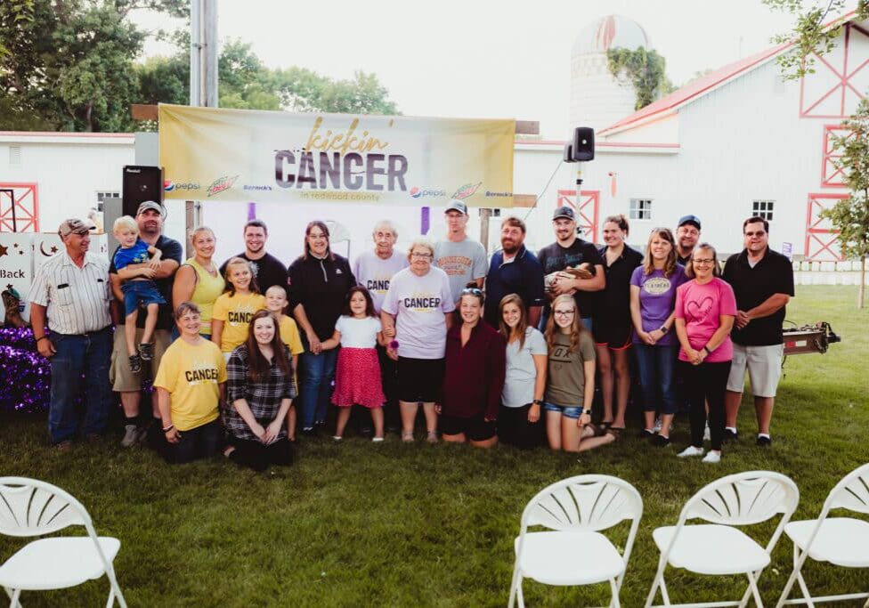 A group of people in front of a kickin' cancer event banner